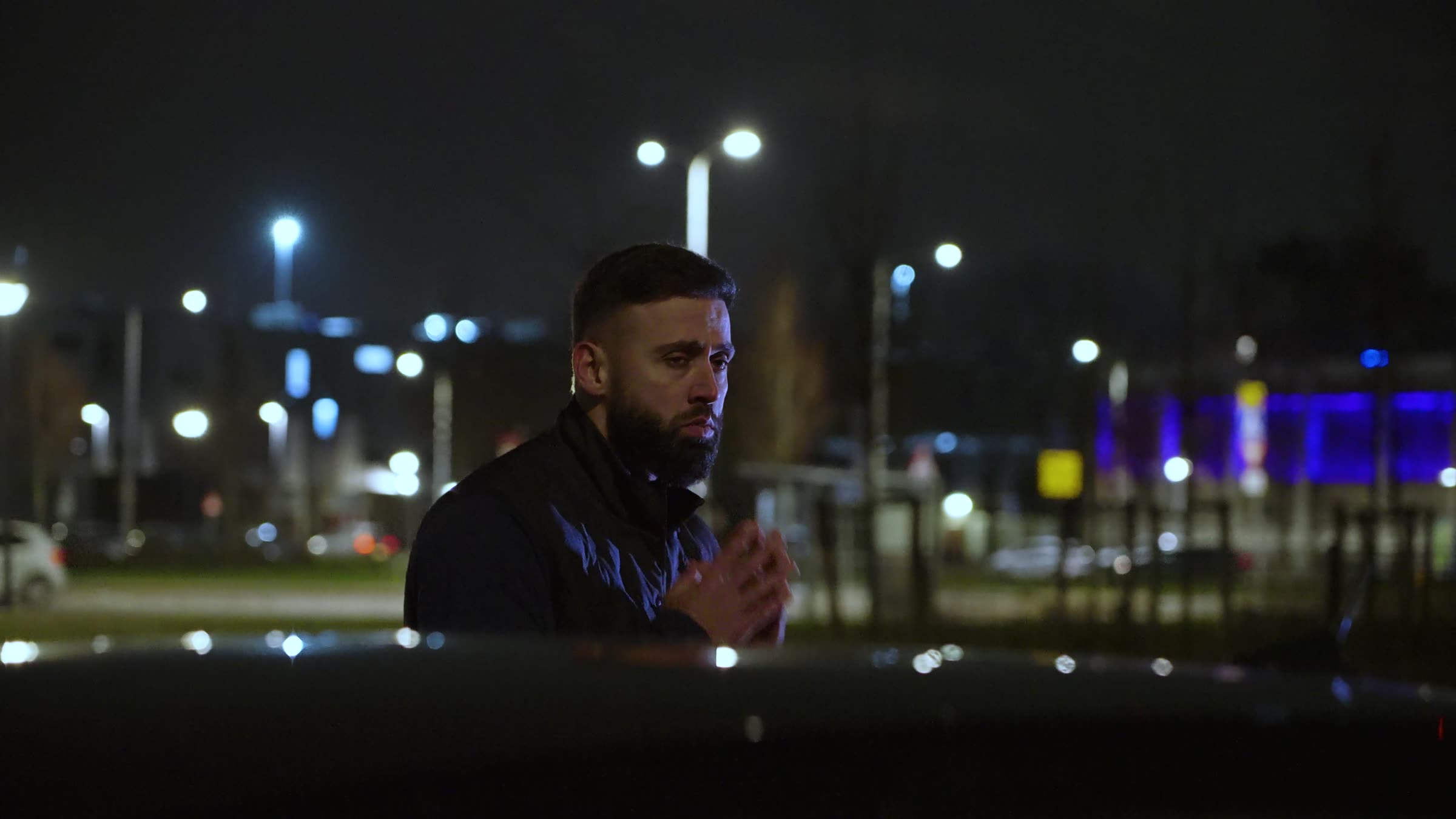 Still uit de trailer: man alleen in de nacht, stadslichten op de achtergrond
