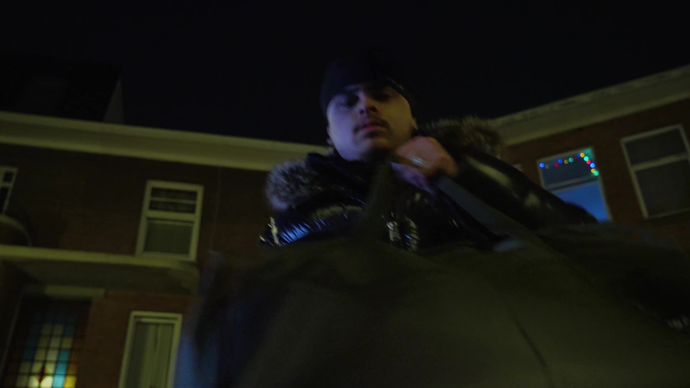 Still uit de trailer: man met capuchon tussen bakstenen huizen